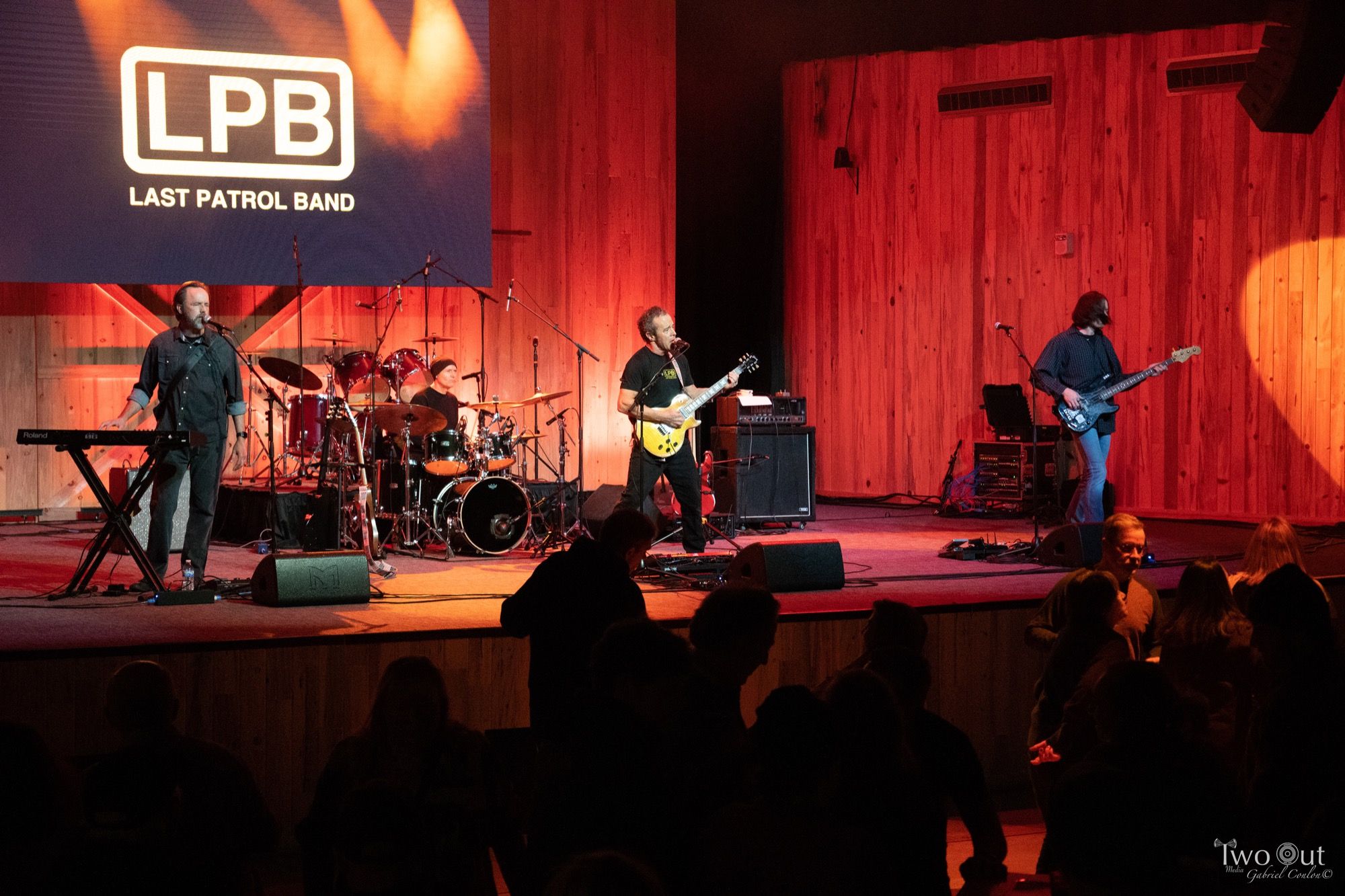 The full band performing on the Boot Barn Hall stage with the LPB screen lit up and the dance floor crowd below