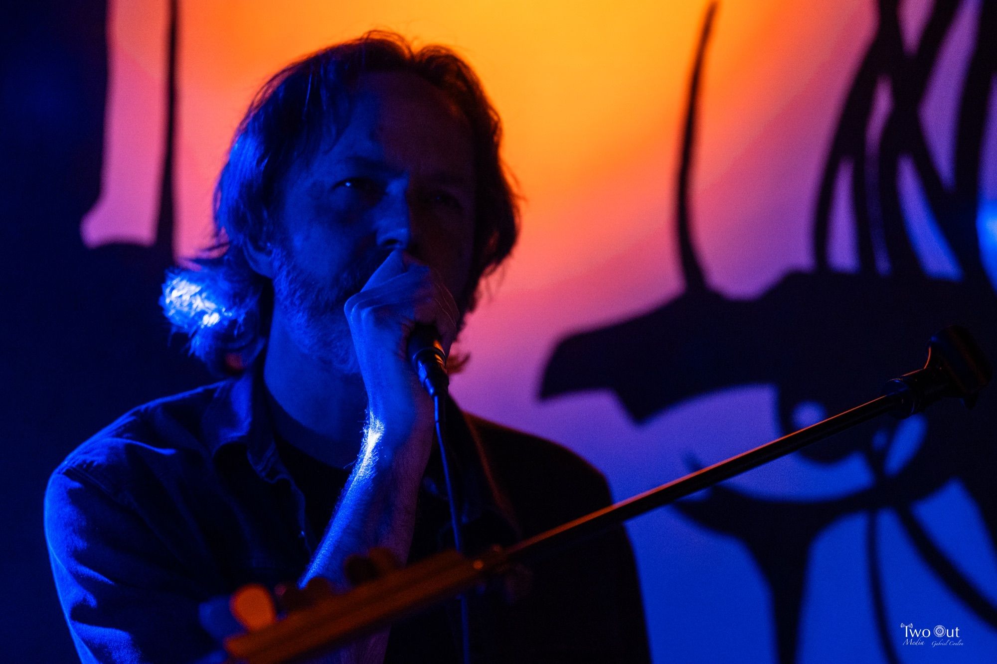 Close-up portrait of the singer lit in orange and blue stage light at Buzzed Crow