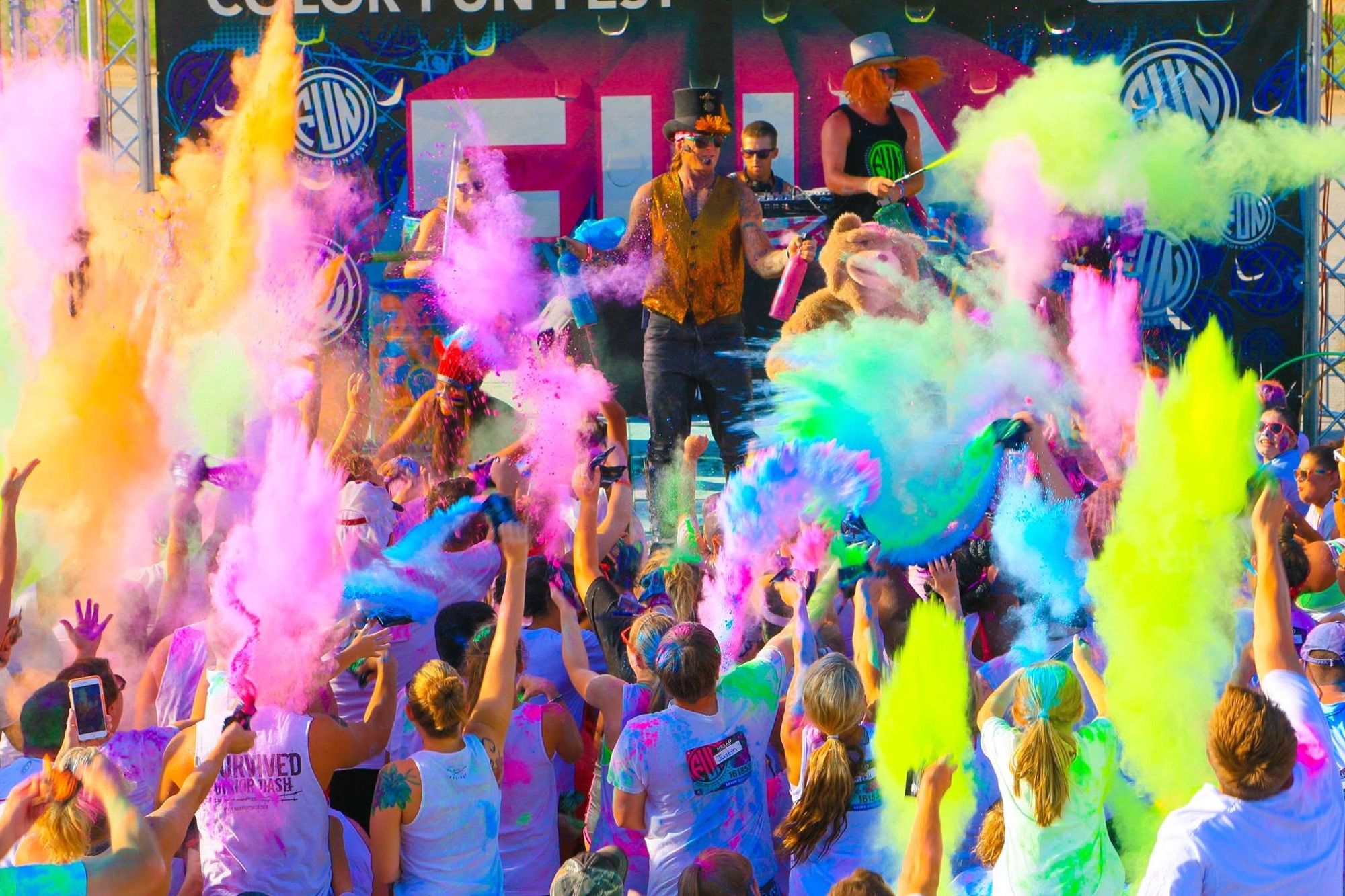 Performer on stage tossing coloured powder over a cheering festival crowd