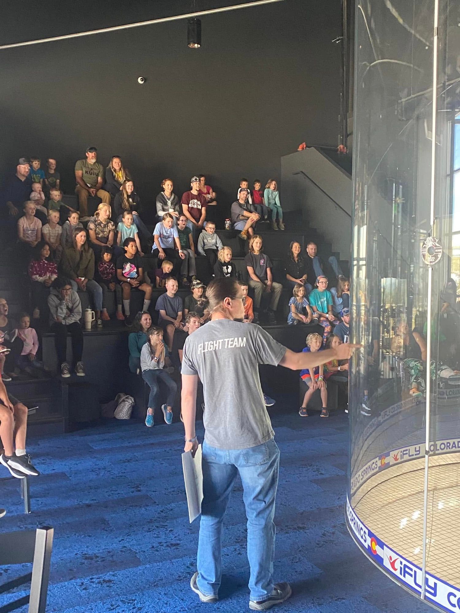 Kids in flight suits raising their hands during a STEM day briefing at iFly