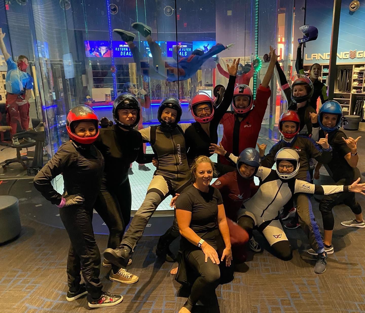 Large group of women cheering and posing together at an iFly location
