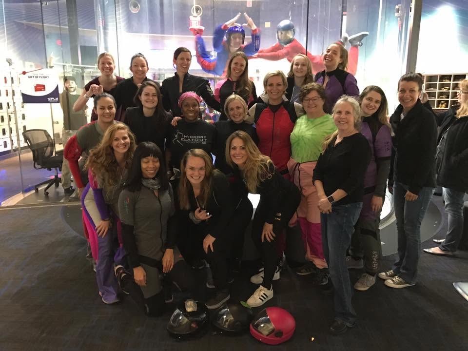 Group of flyers in helmets posing together near the flight gear shop