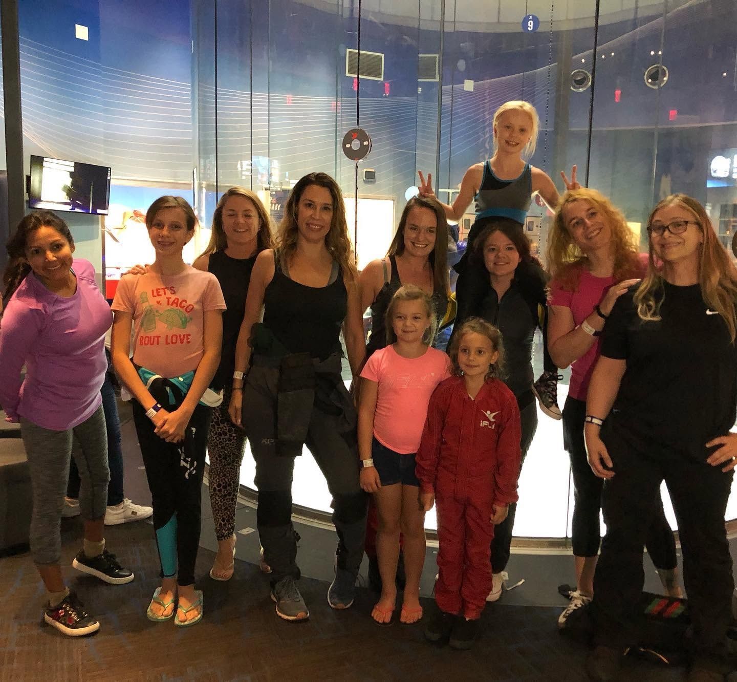 Large group of women and girls of different ages posing together in an iFly lobby