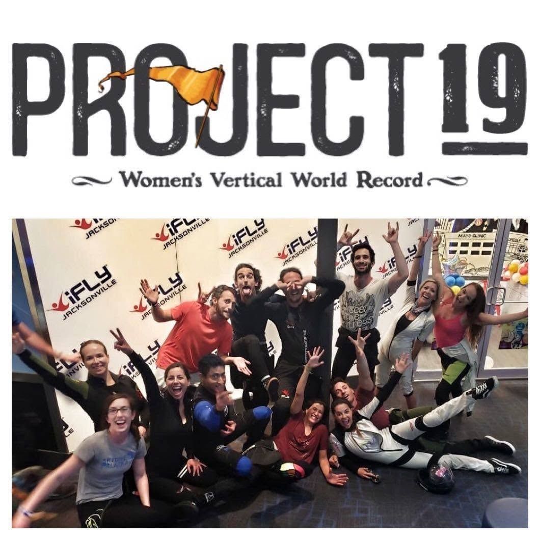Group of flyers celebrating together in front of a Project 19 women's vertical world record banner