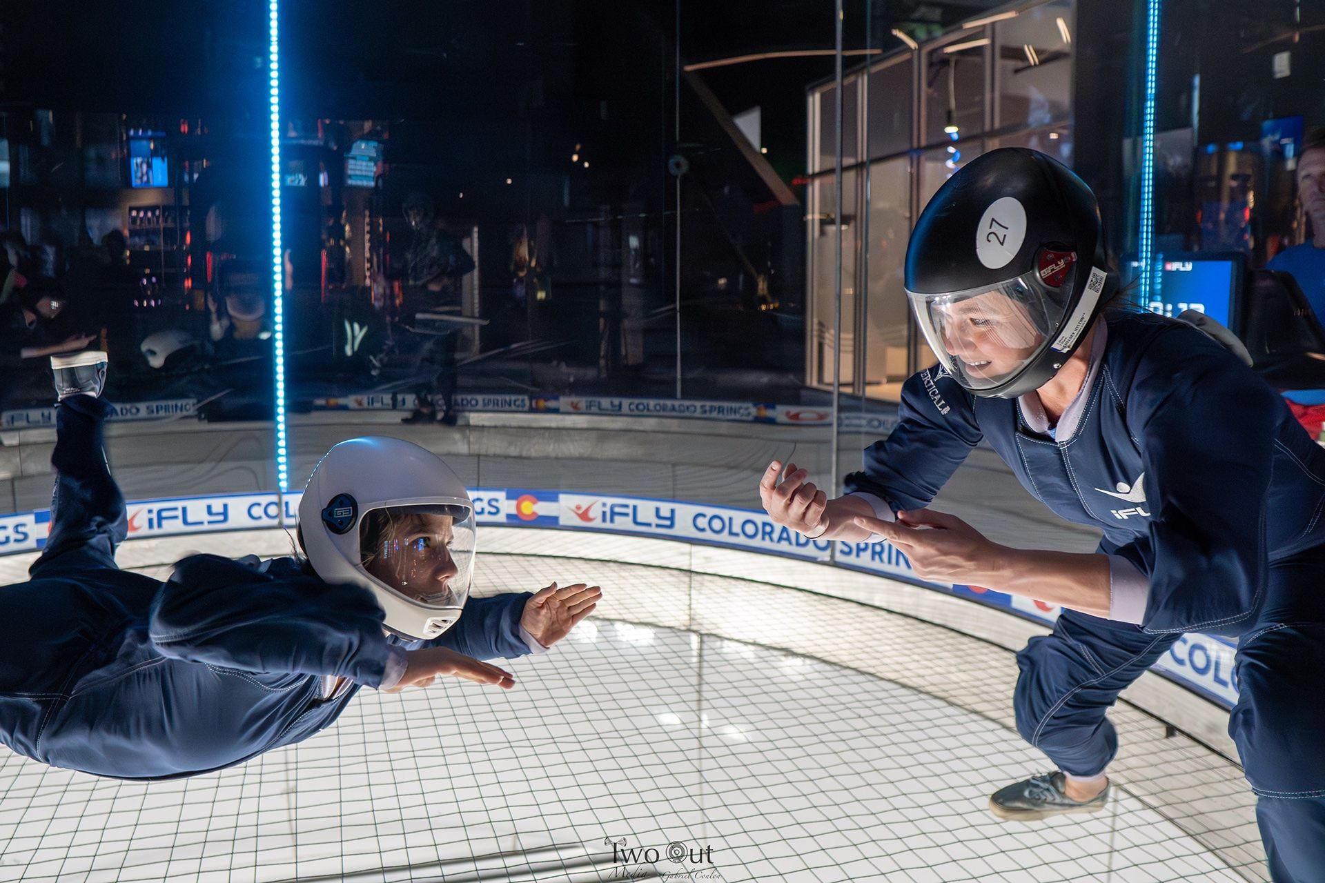 Two flyers reaching for each other's hands mid-air in the tunnel