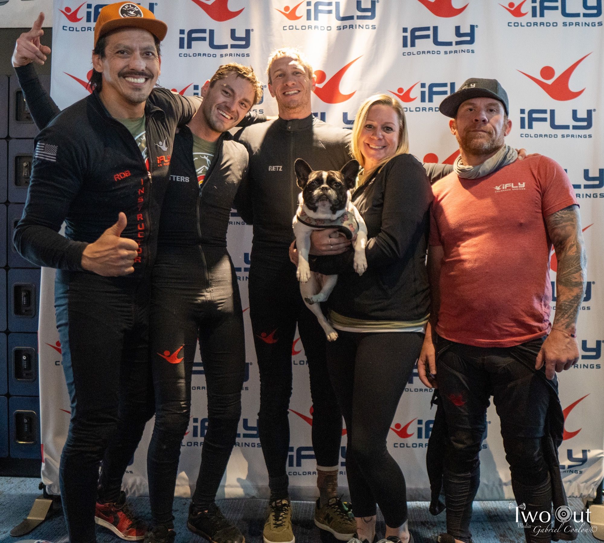 iFly Colorado Springs staff group posing with a French bulldog at the step-and-repeat banner