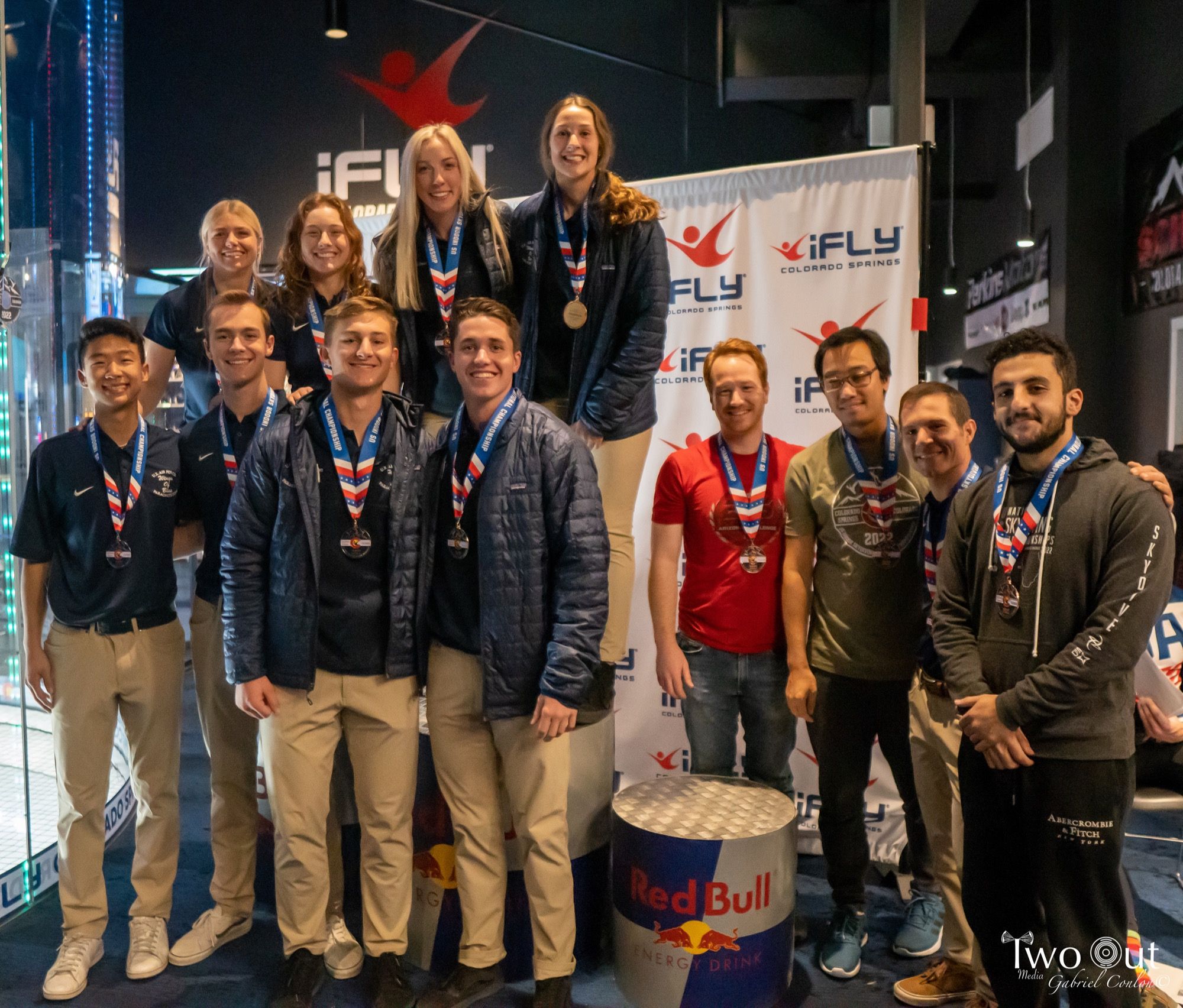 Team posing with their medals around their necks in front of the step-and-repeat
